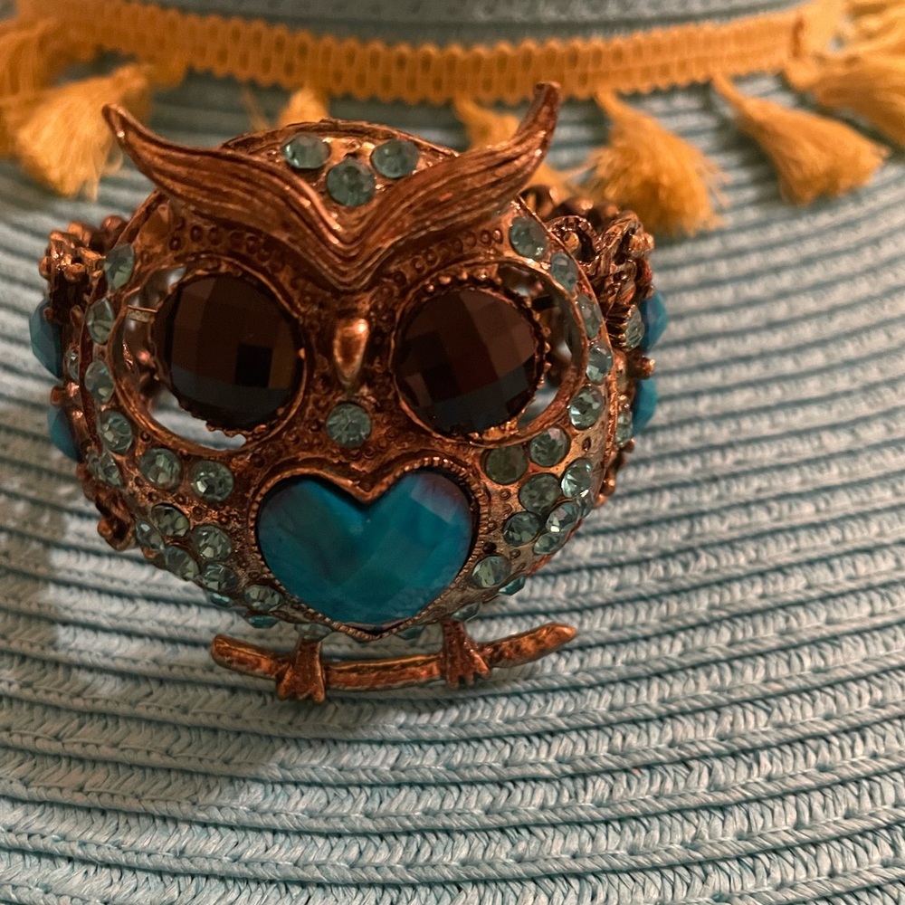 It’s a beautiful owl face bracelet. It’s gold and turquoise in color.